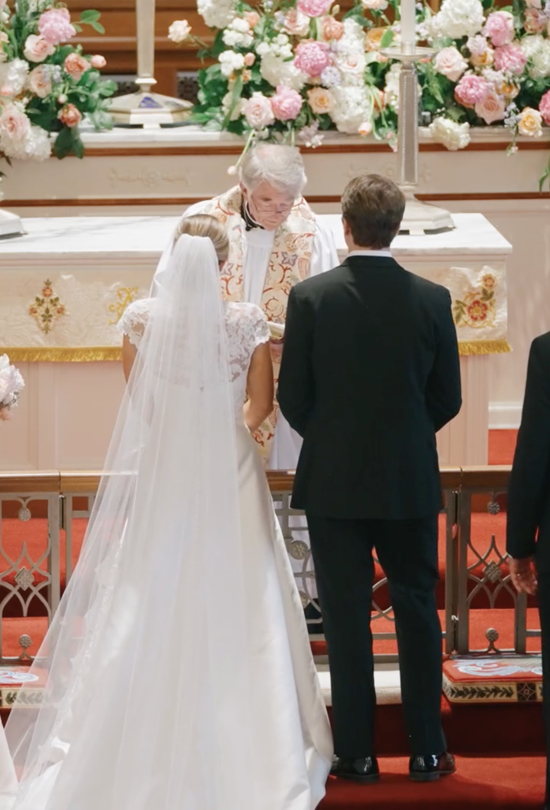 Bride and groom exchanging vows at church altar with floral arrangement